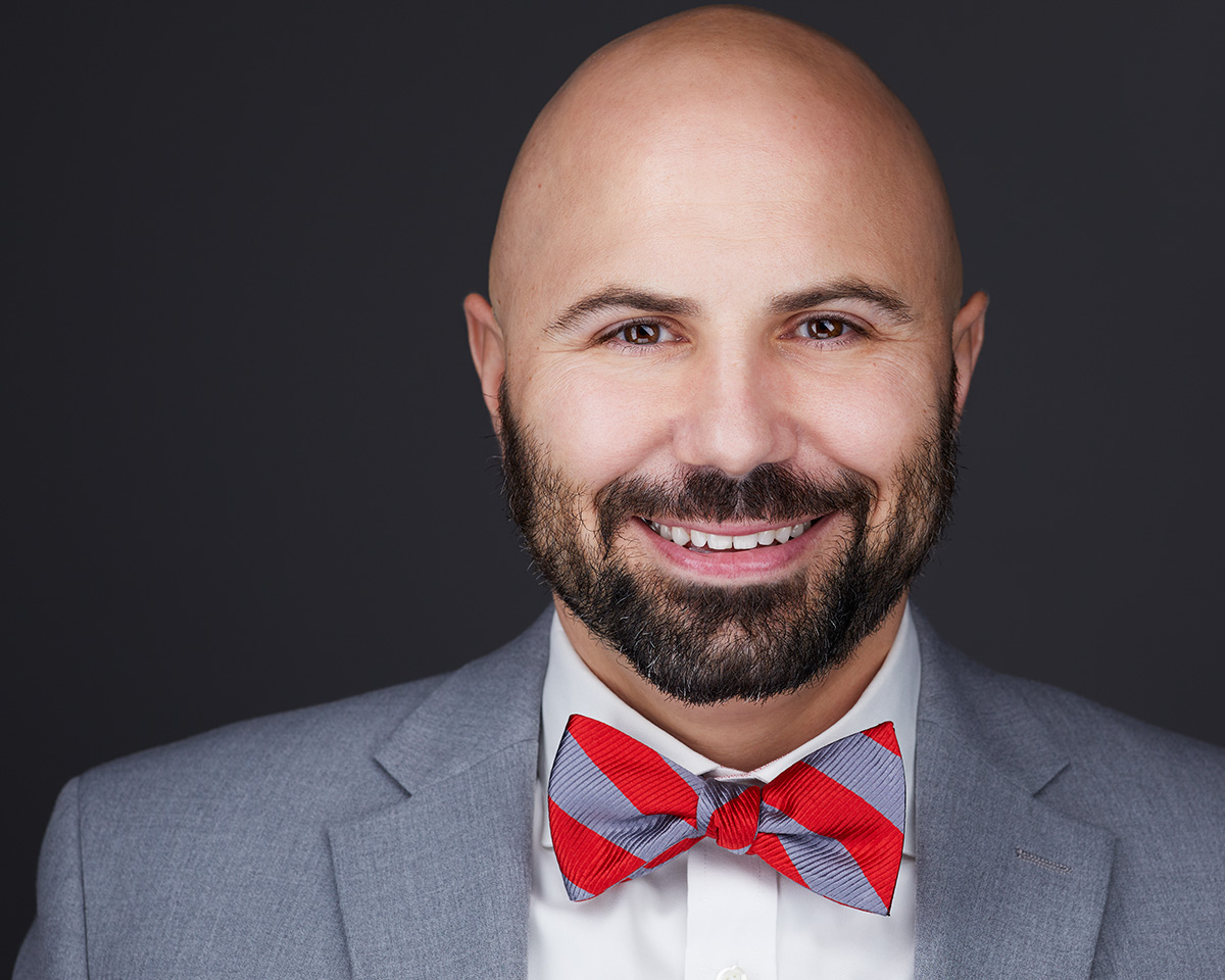 Young bald Male Professional Headshot with a gray jacket and a gray and red bowtie in Alexandria Virginia